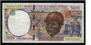 5000 Francs.

Serial -N- prefix (Equatorial Guinea).

Laborer wearing hard hat and riggers with well drill at right on face; woman with head basket at left, gathering cotton at center on back.

Pick #504N-d Banknote