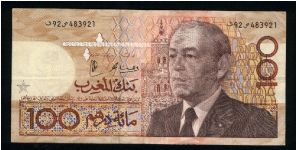 100 Dirhams.

Older bust of King Hassan II at right, mosque in background on face; demonstration and coral at center on back.

Pick #65 (signature not reported) Banknote
